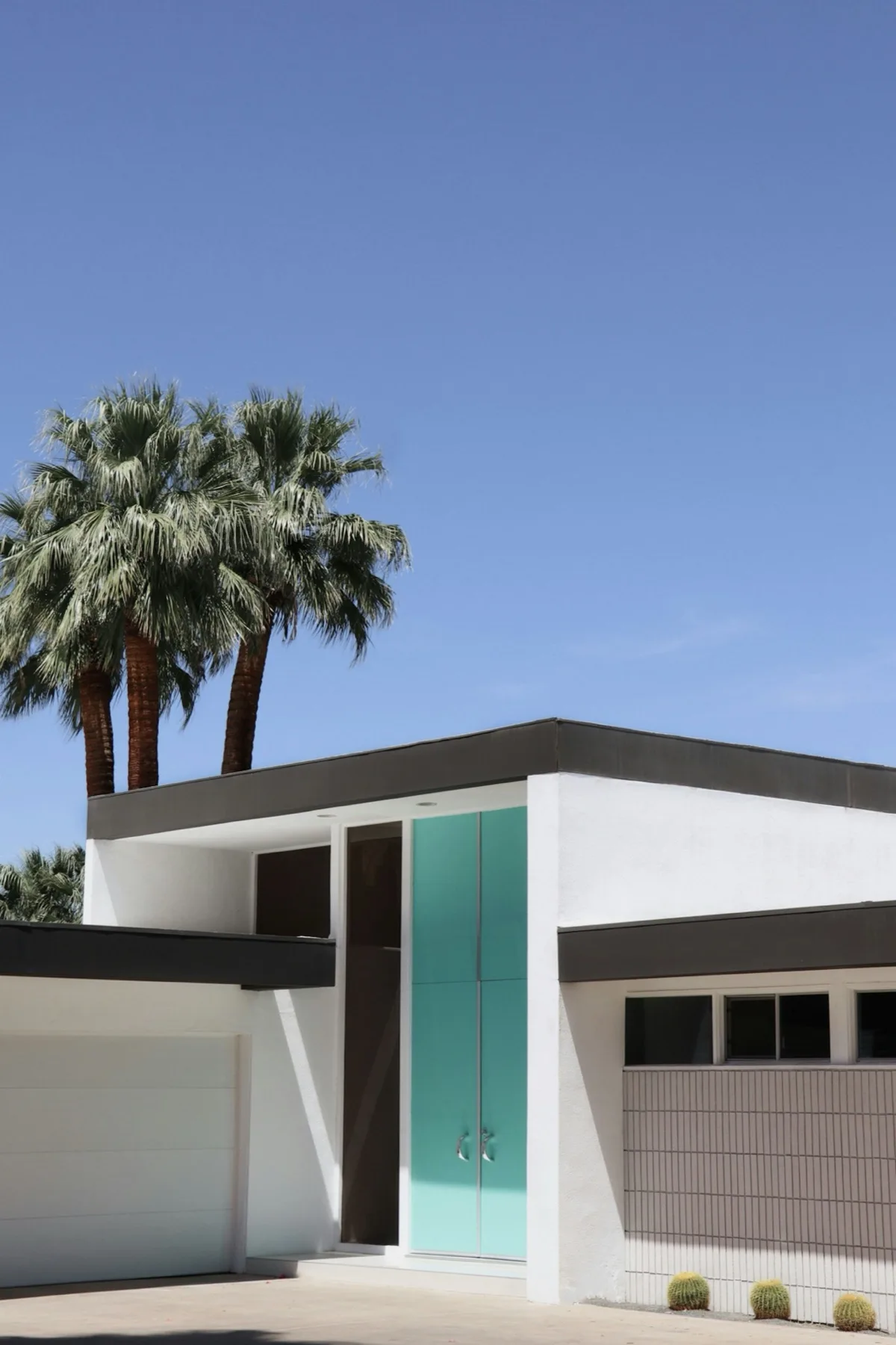 Teal front door on a midcentury modern home in Palm Springs with desert plants and clear blue sky