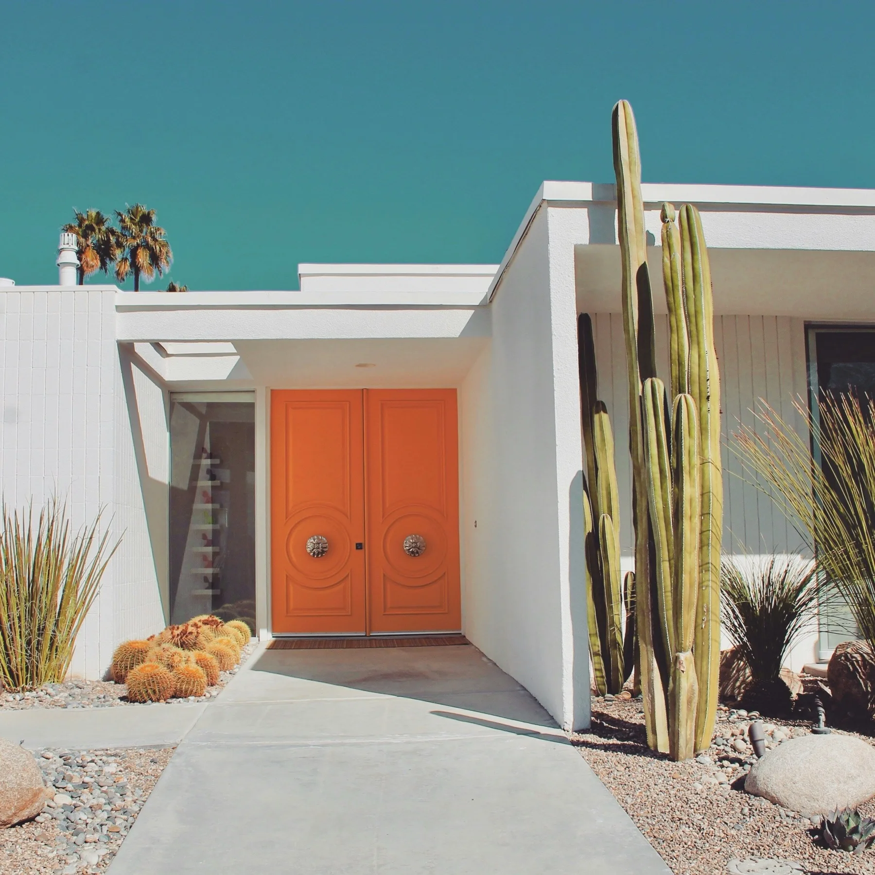 Vibrant orange door on a midcentury modern home in a Palm Springs neighborhood