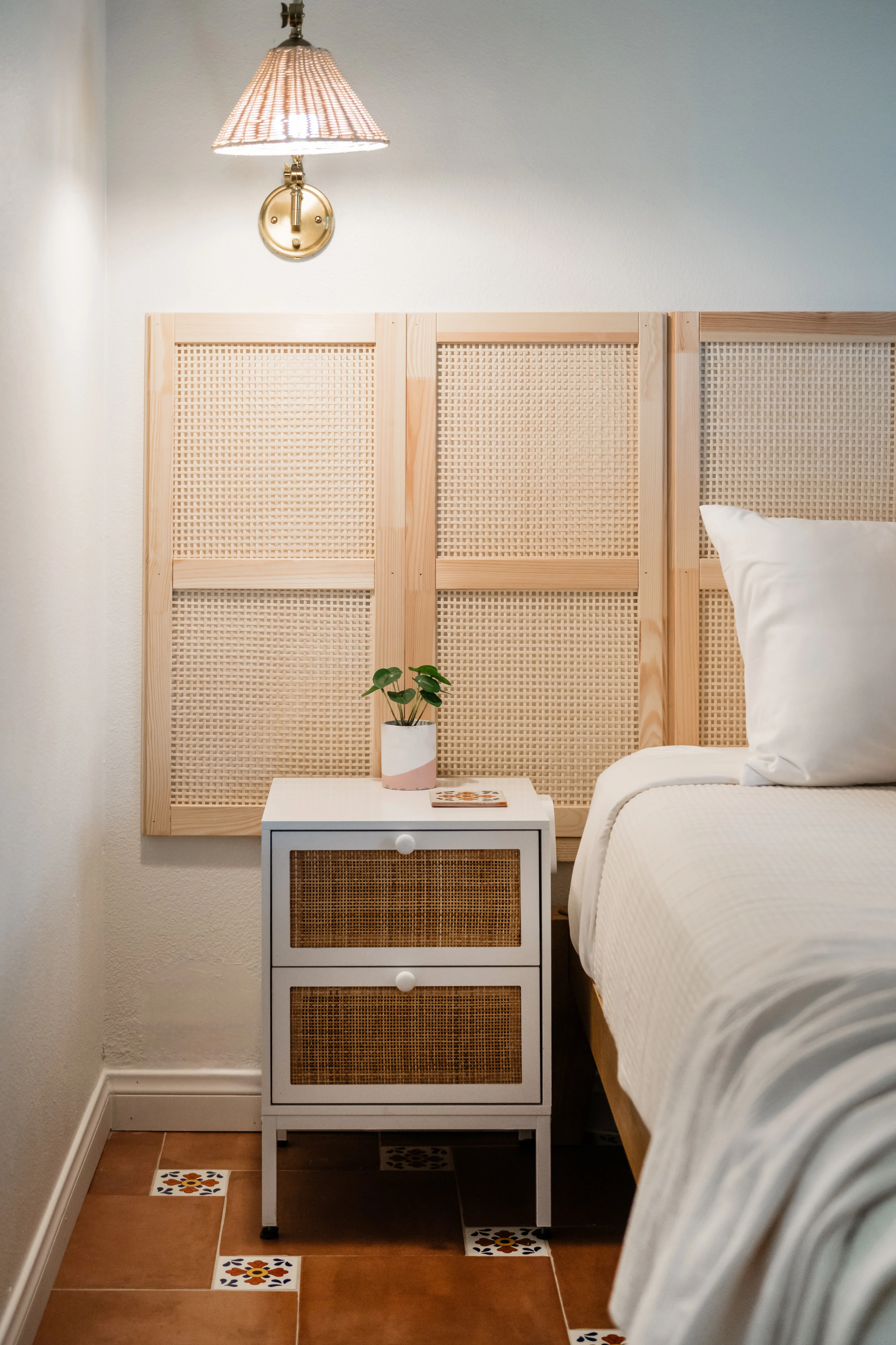 IKEA IVAR bamboo panel headboard close-up in the Cali Room at Terra Luz, with brass sconce, white rattan nightstand, and Talavera tile floor in Indio California