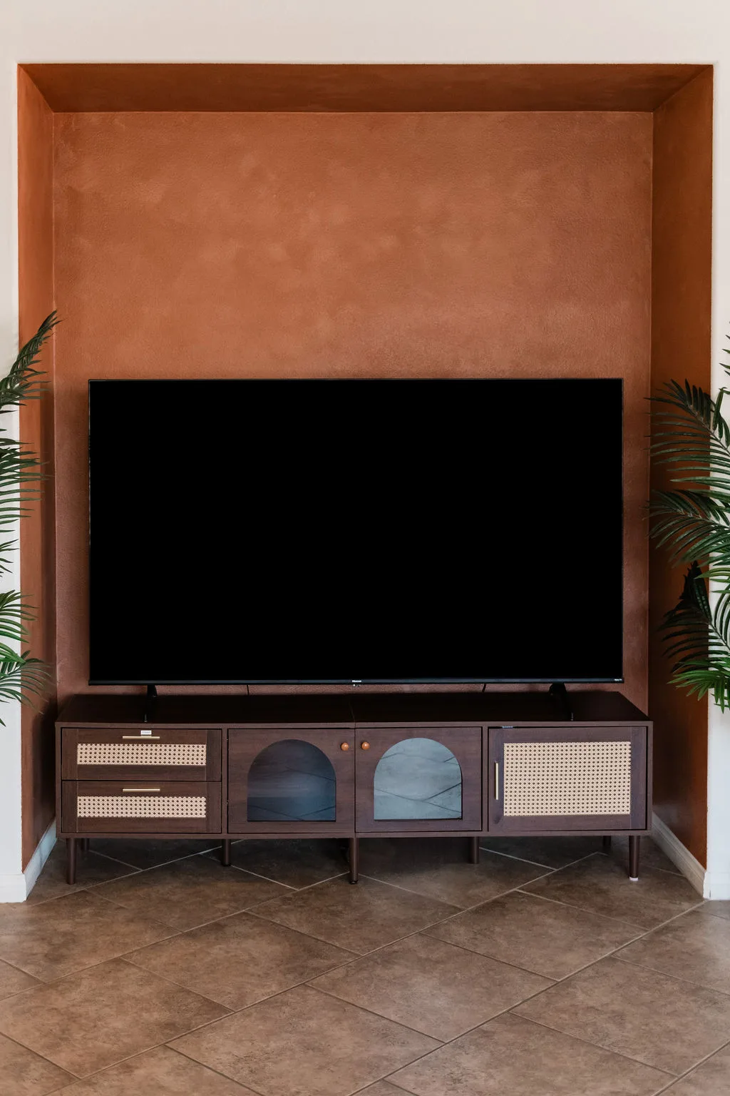 Terra Luz terracotta lime-wash TV niche with walnut credenza and tropical plants in the living room