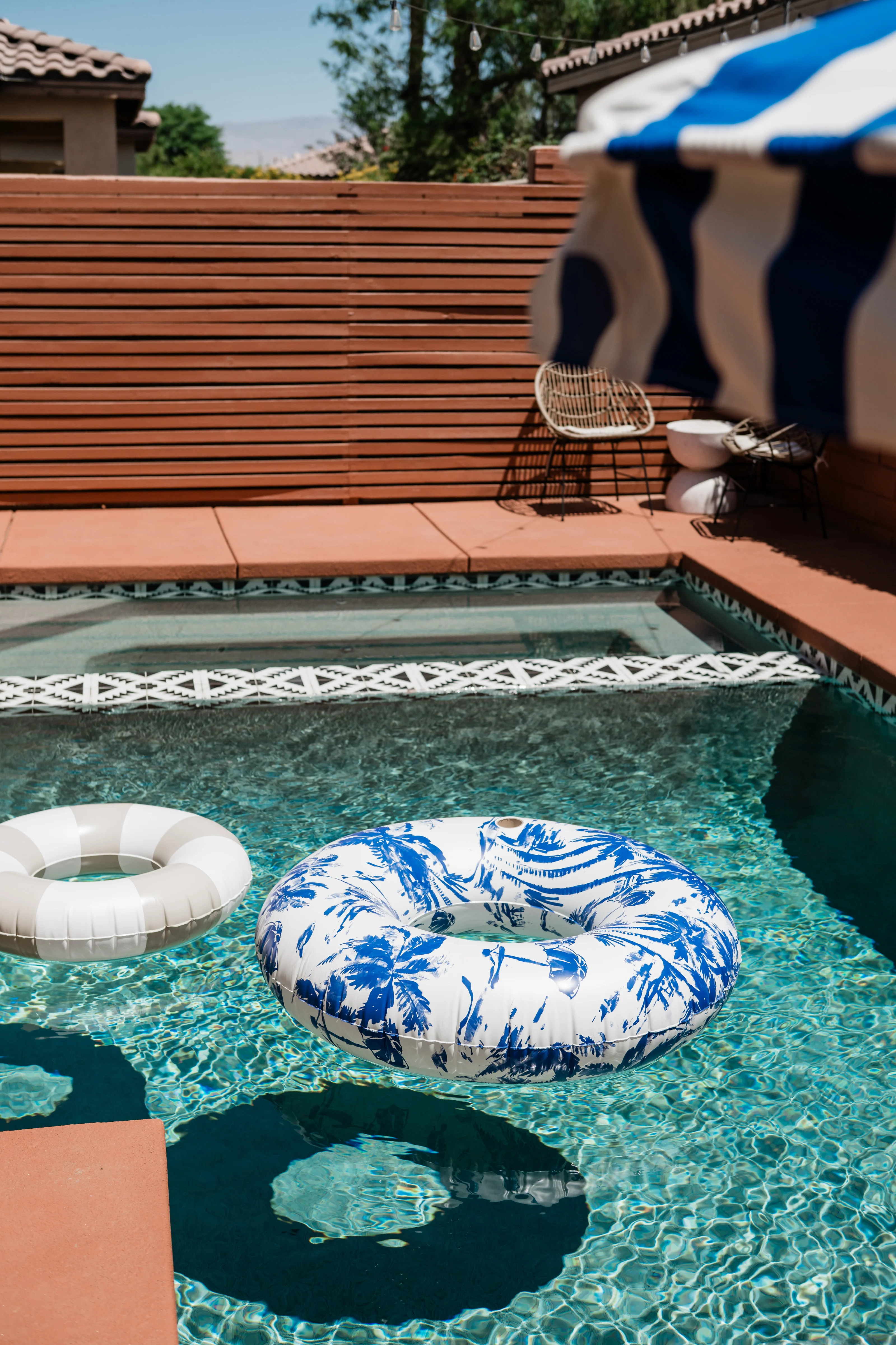 Terra Luz pool with wood slat fence backdrop, wire rattan chairs, and Frida Kahlo blue pool in Indio California