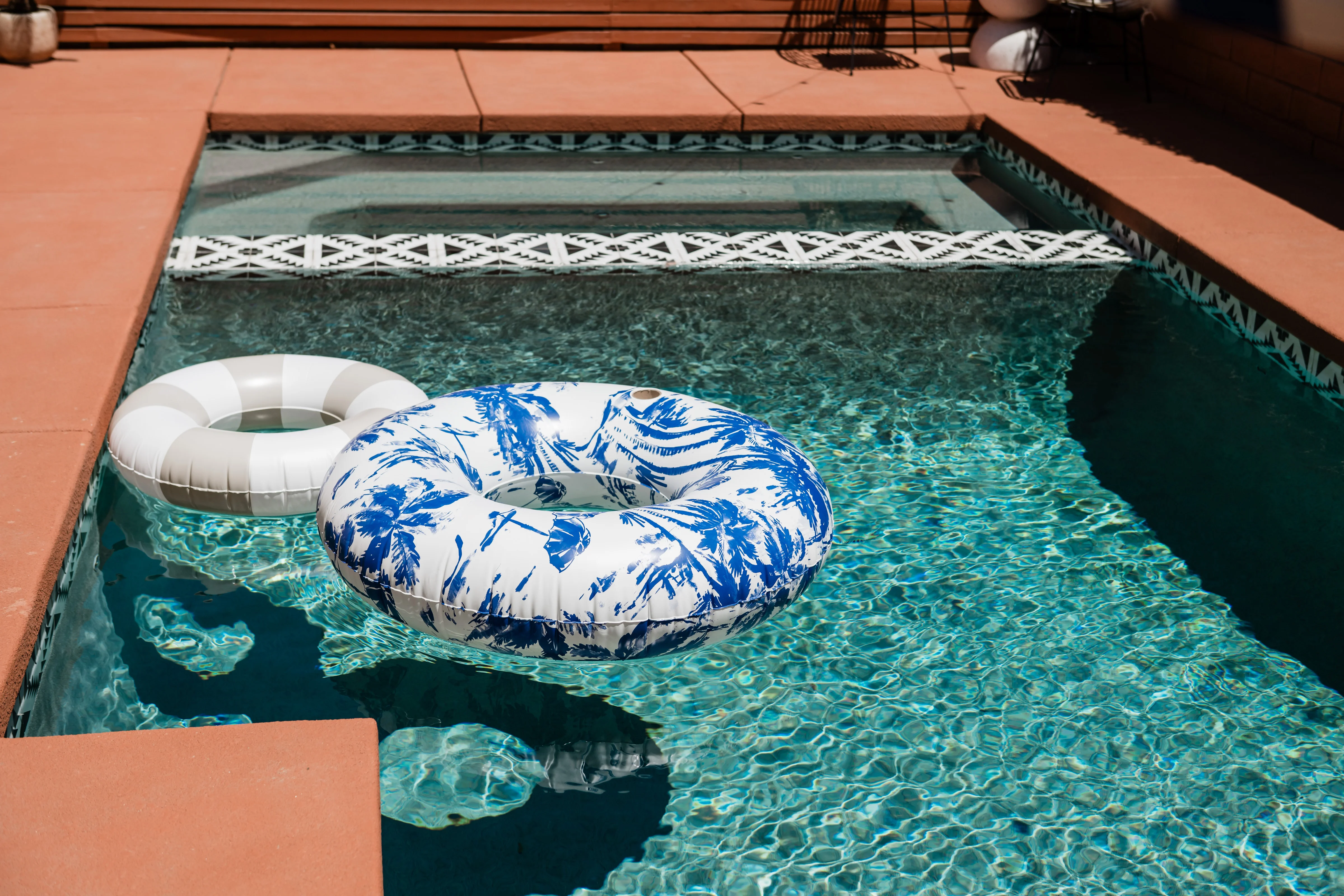 Terra Luz backyard with Frida Kahlo blue pool, striped umbrella, outdoor sectional, and pergola with string lights in Indio California