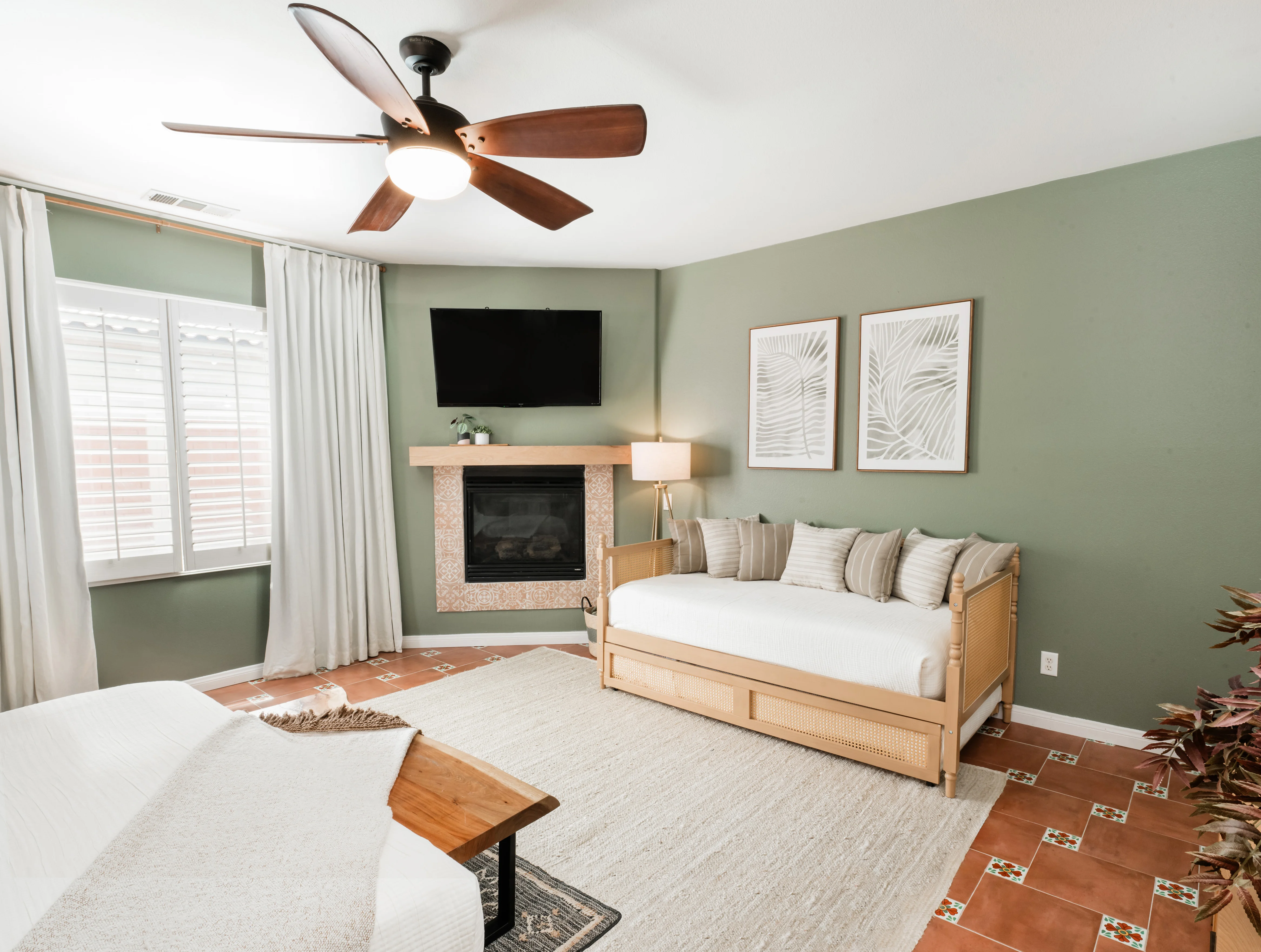 Primary bedroom at Terra Luz with king bed frame and pull-out trundle bed extended on the floor, sage green walls, terracotta Talavera tile floor in Indio California