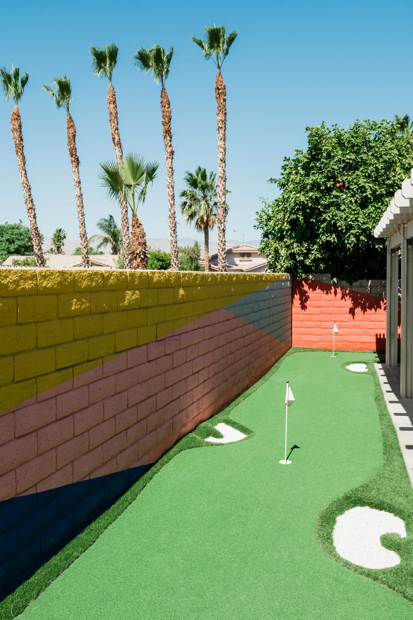 2-hole putting green with colorful painted block wall at Cozy Cactus Indio