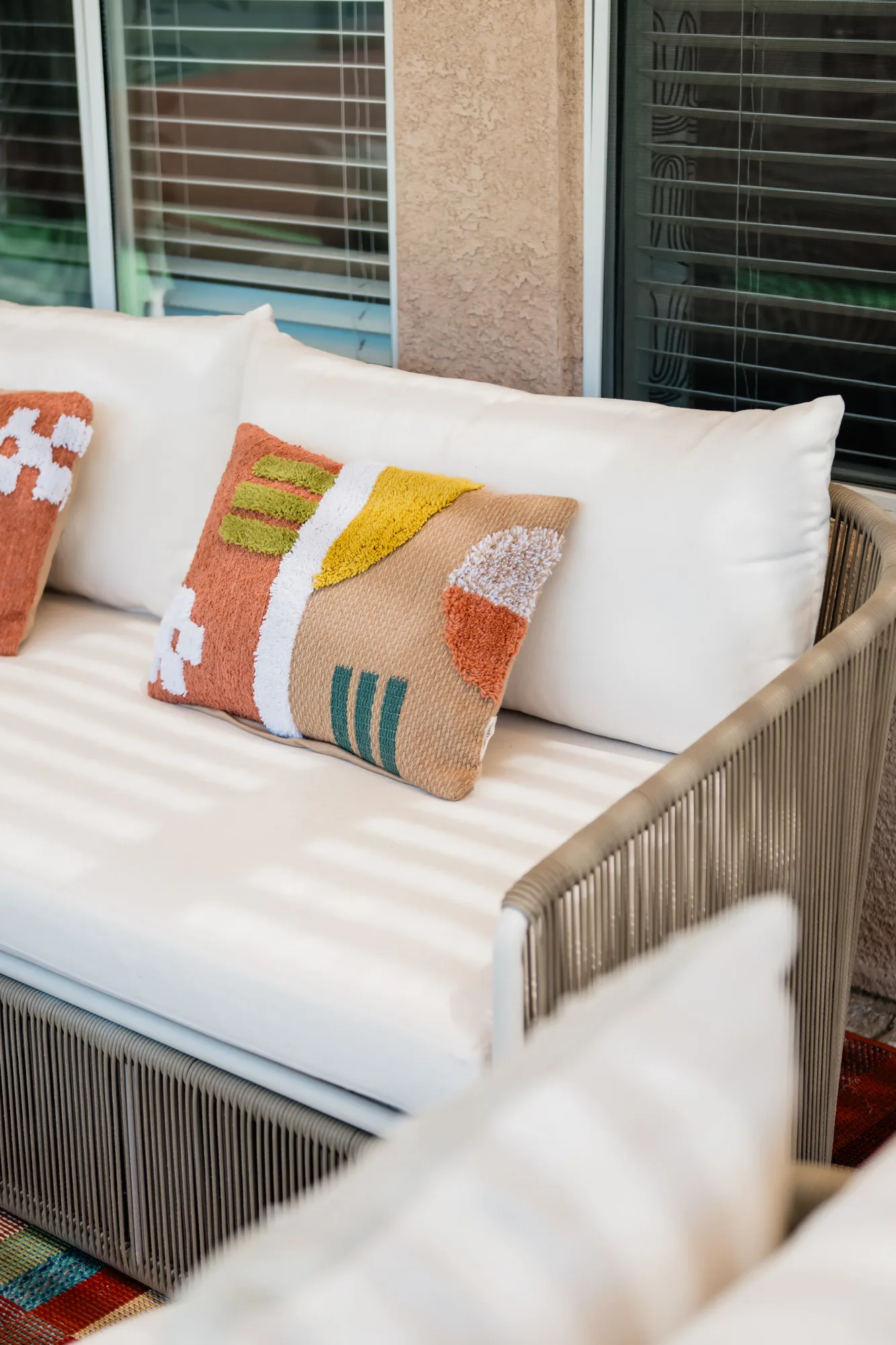 Outdoor rope sofa under pergola with colorful throw pillows at Cozy Cactus
