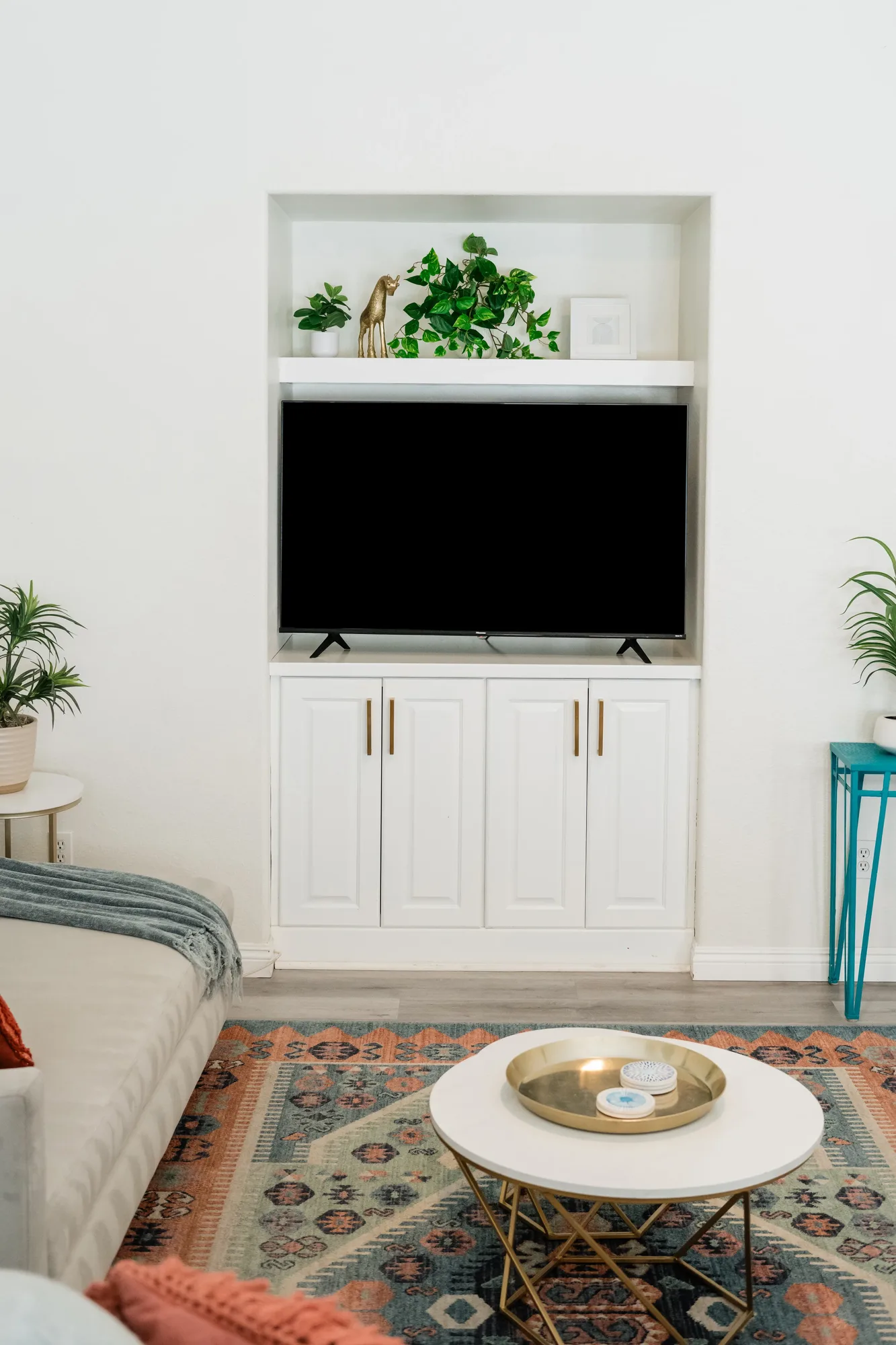 Cozy Cactus living room TV niche close-up with white built-in cabinets and gold hardware