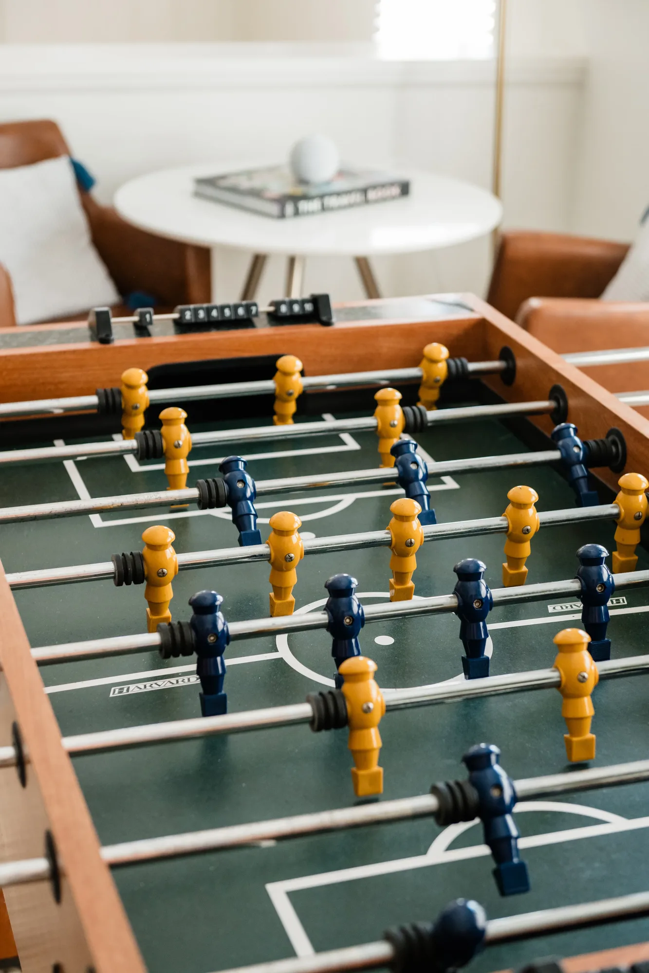 Cozy Cactus foosball table close-up with round dining table and leather chairs in background