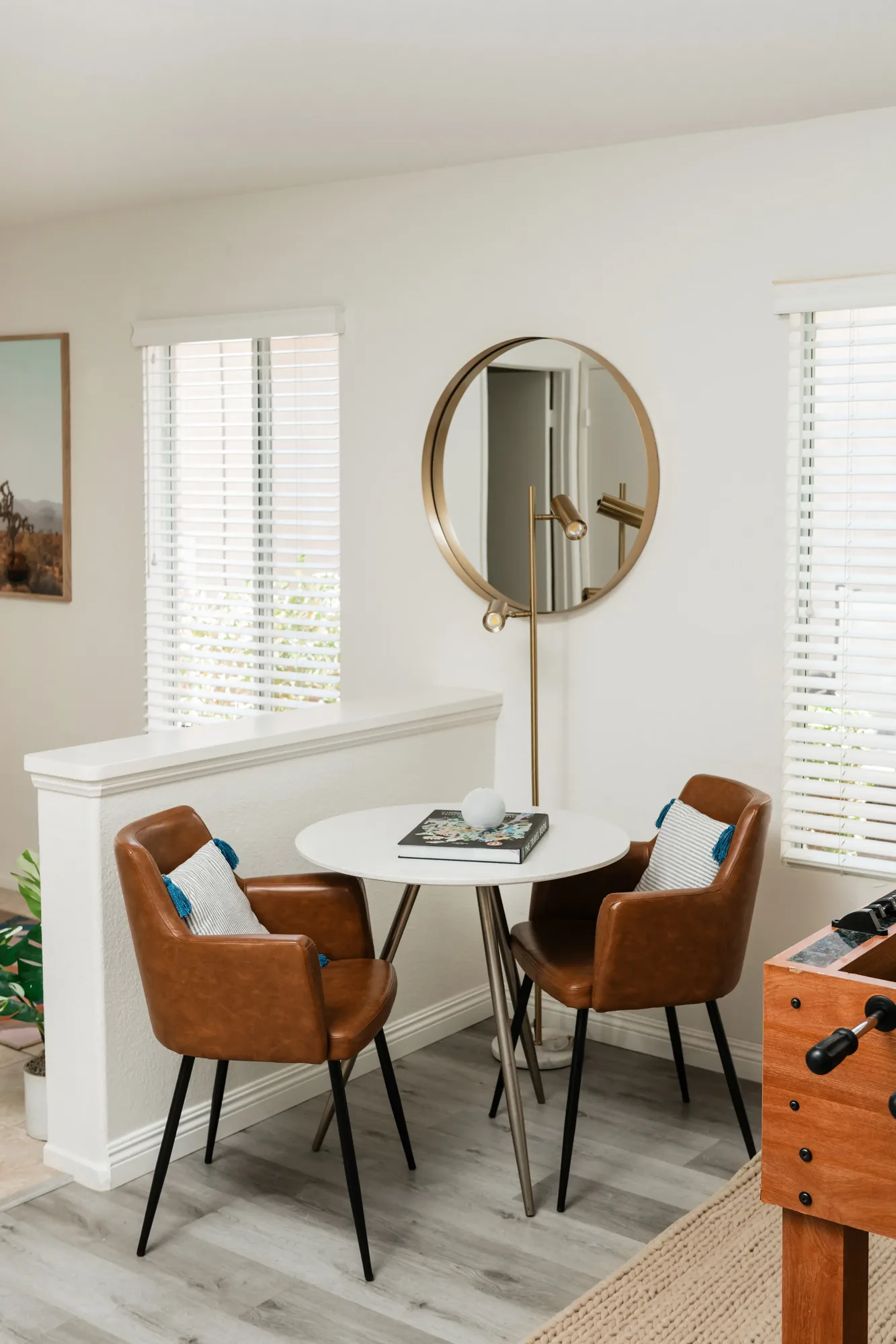 Cozy Cactus dining area with round white table, tan leather chairs, and gold mirror