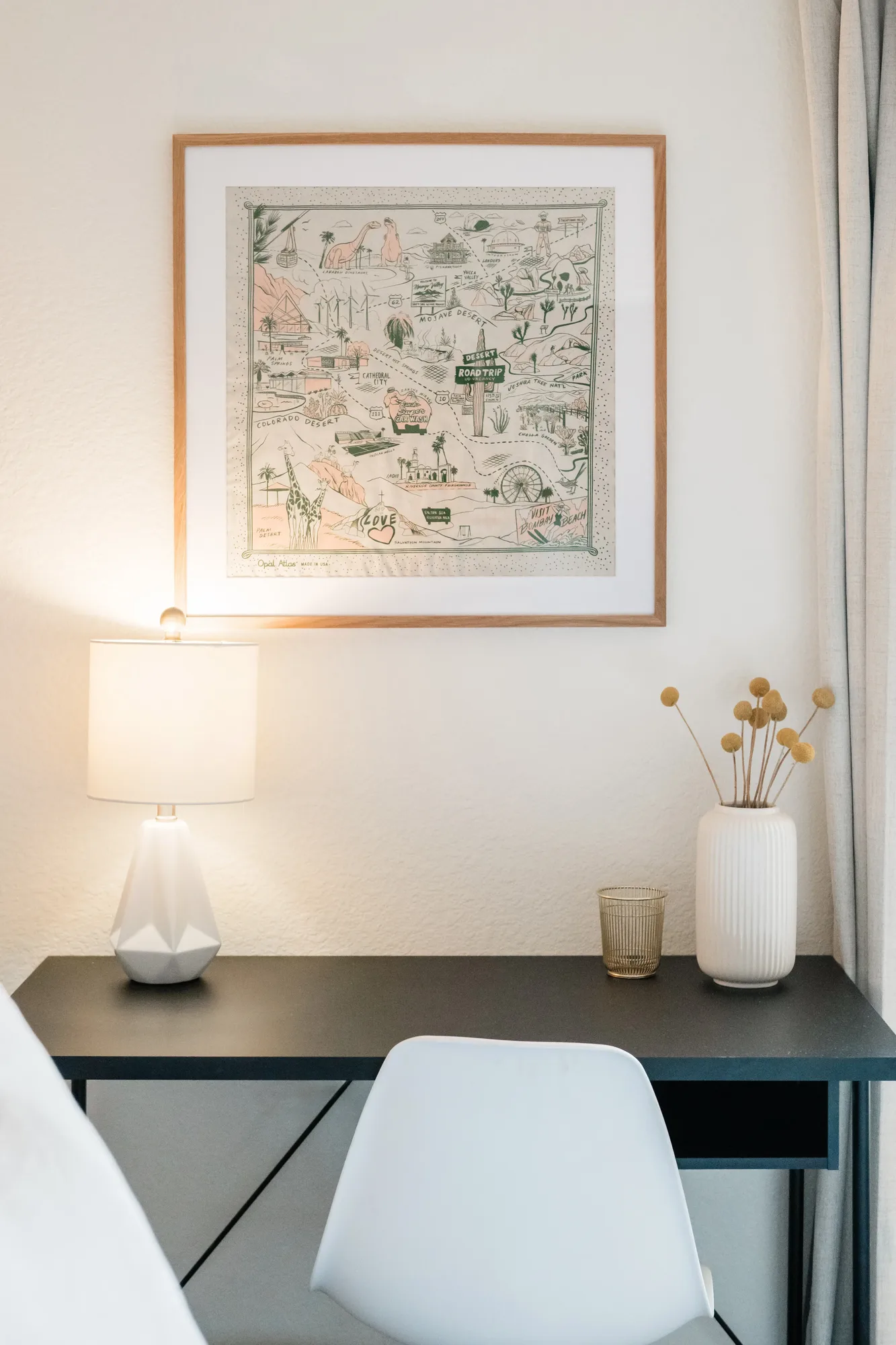 Cozy Cactus bunk bedroom desk detail with Palm Springs illustrated map art, white lamp, and mustard vase