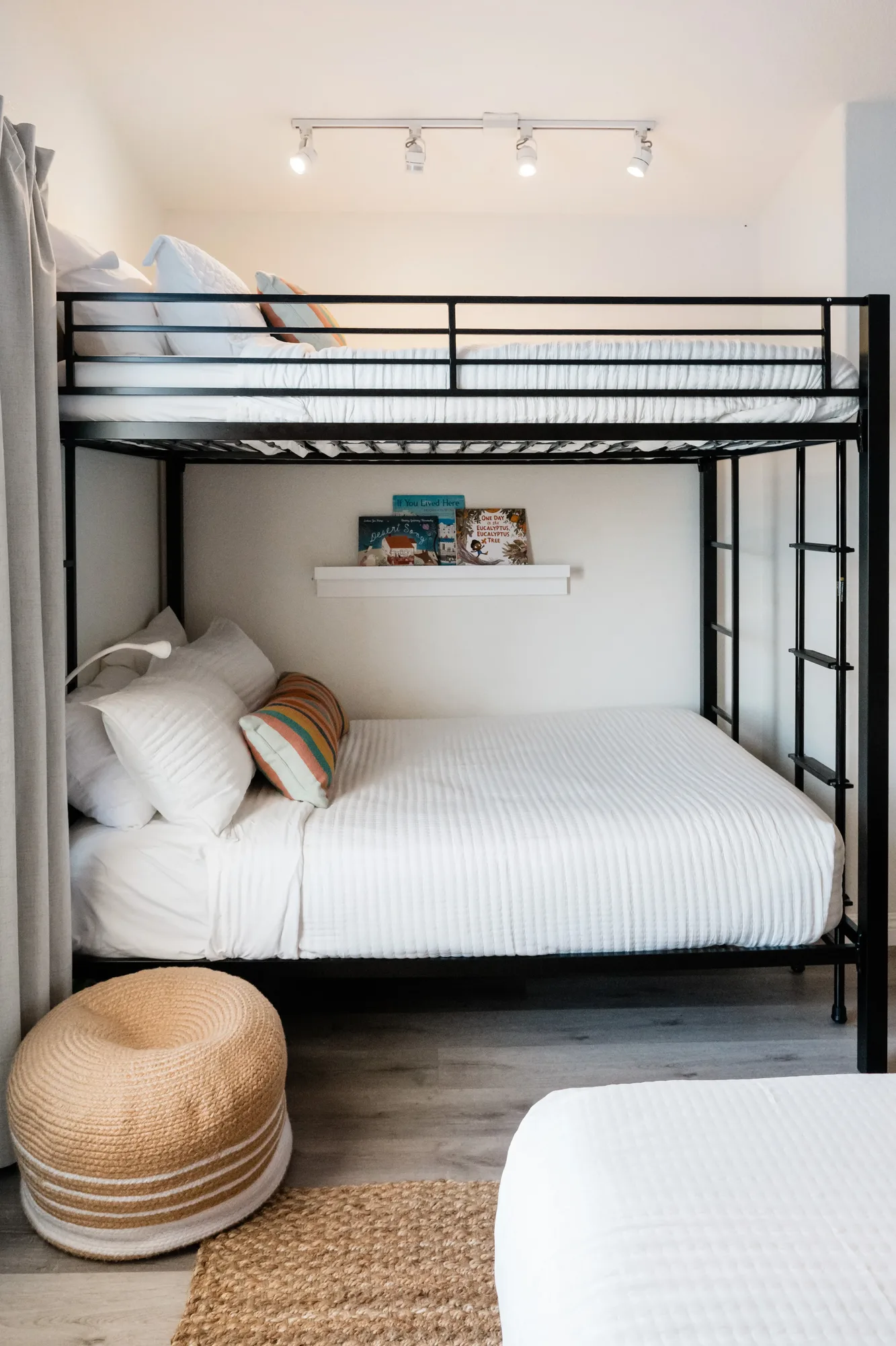 Cozy Cactus black metal bunk beds with white bedding and book ledge