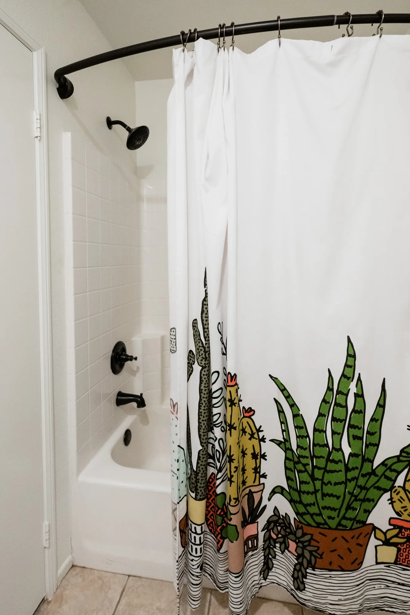 Cozy Cactus bathroom with cactus shower curtain, soaking tub, and black fixtures