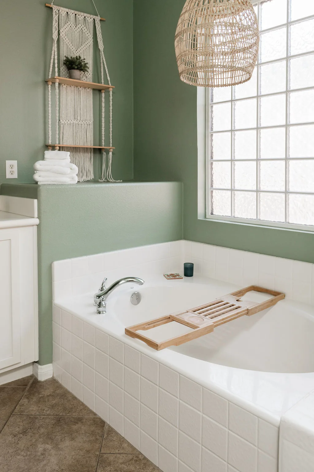 Terra Luz primary bathroom with soaking tub, rattan pendant light, macrame wall hanging, and sage green walls