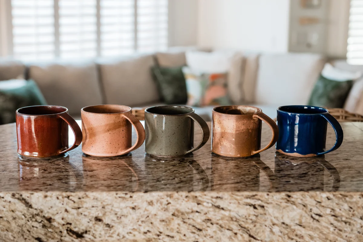 Terra Luz kitchen Leigh Dierck handmade ceramic mugs in earth tones lined up on granite counter