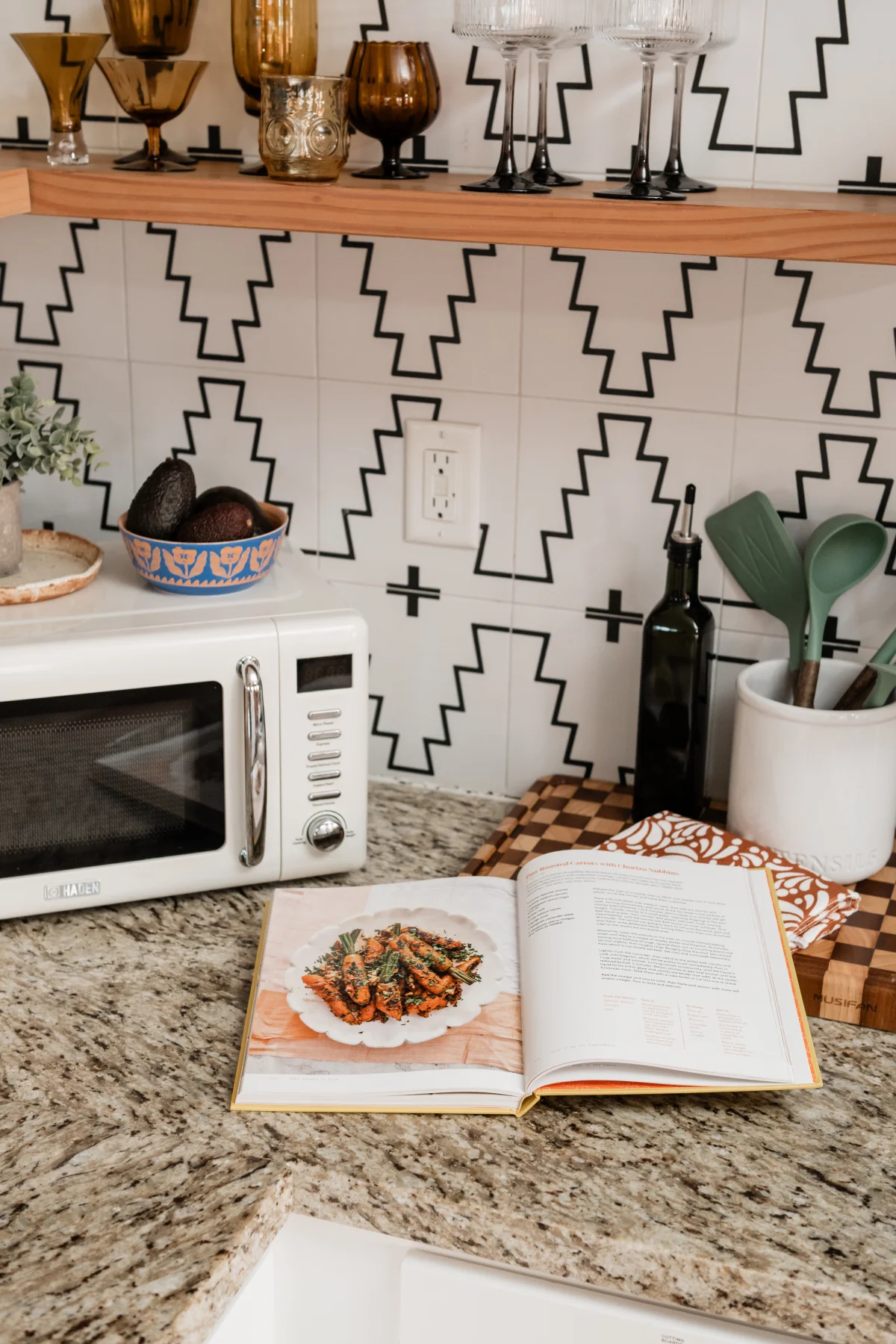 Terra Luz kitchen backsplash view showing microwave, open cookbook, glassware on floating wood shelves