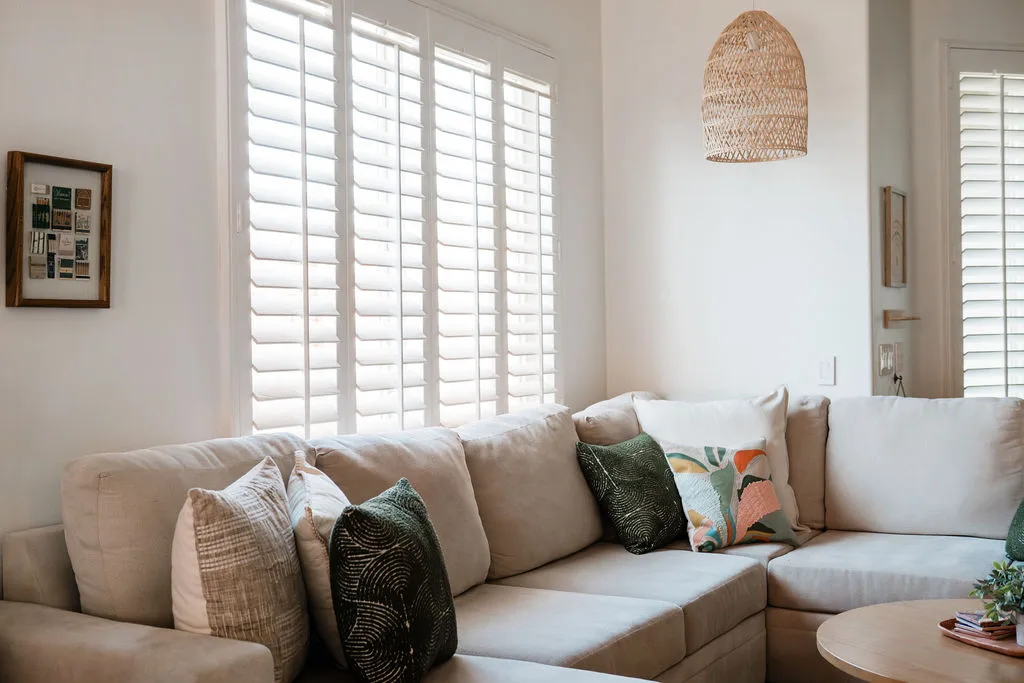 Terra Luz living room with sectional sofa, plantation shutters, and woven rattan pendant light