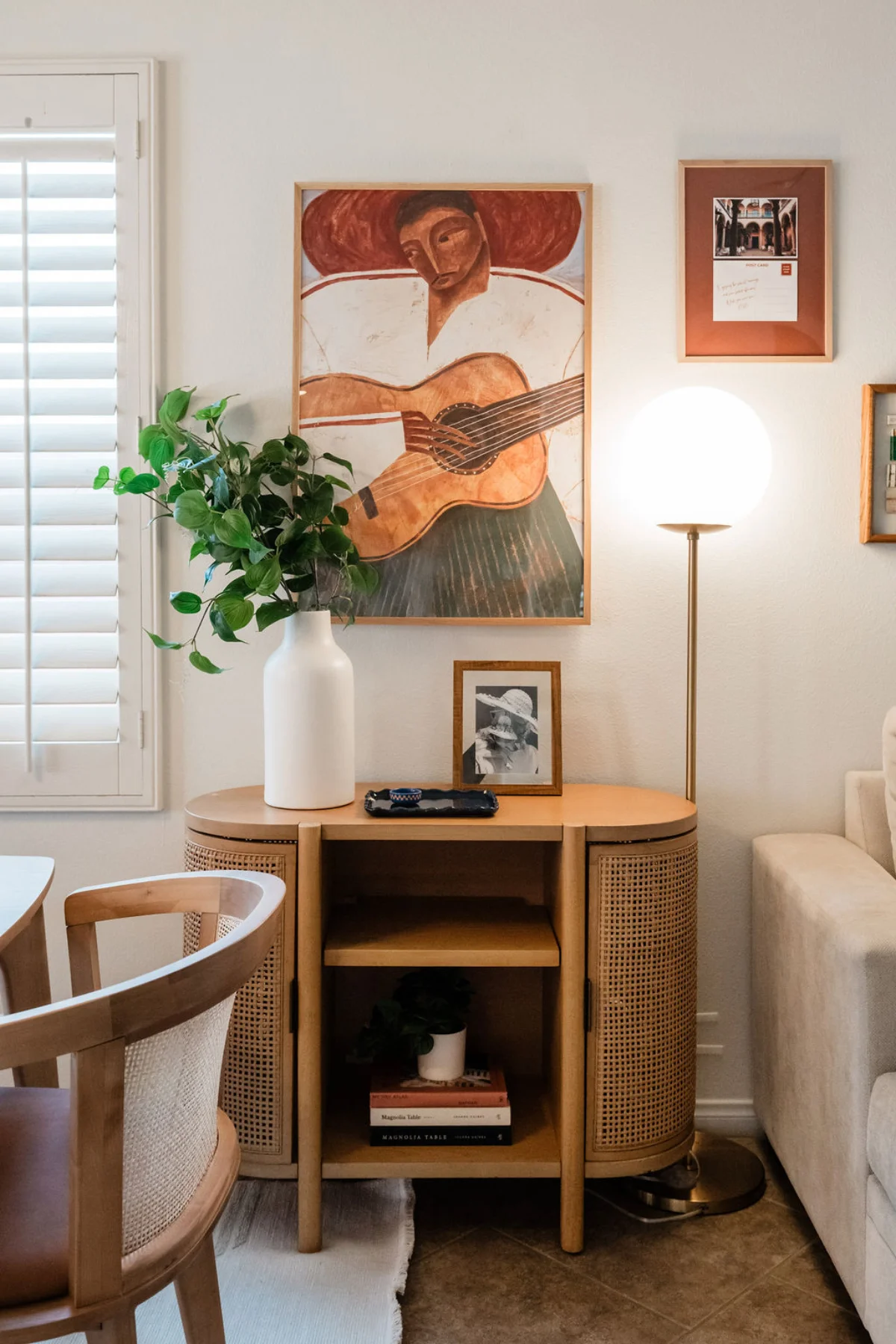 Terra Luz living room rattan console table with guitar player painting, white vase, and globe floor lamp