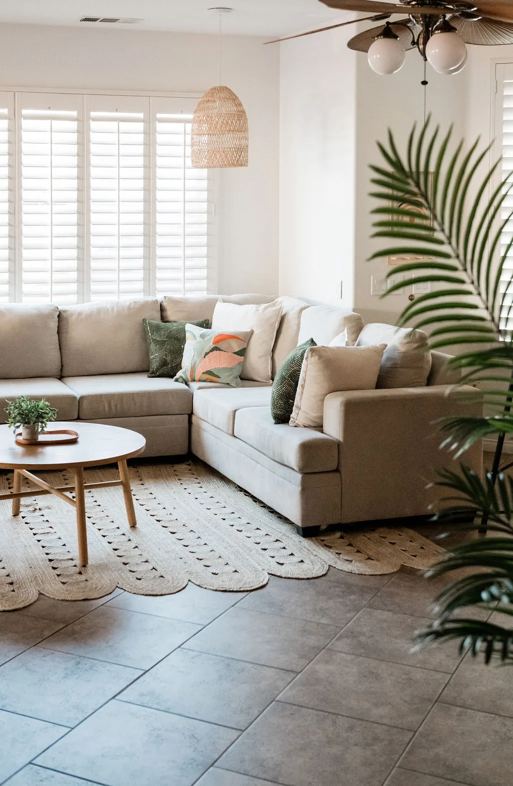 Terra Luz living room with sectional sofa, rattan pendant light, jute rug, and tropical plants