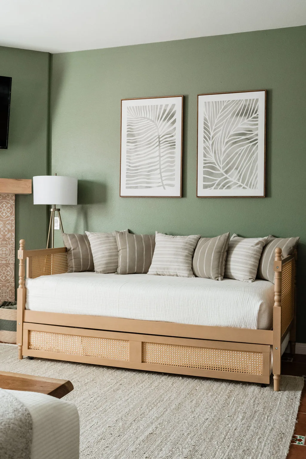 Terra Luz primary bedroom sitting area with cane daybed, two palm frond prints, and sage green walls