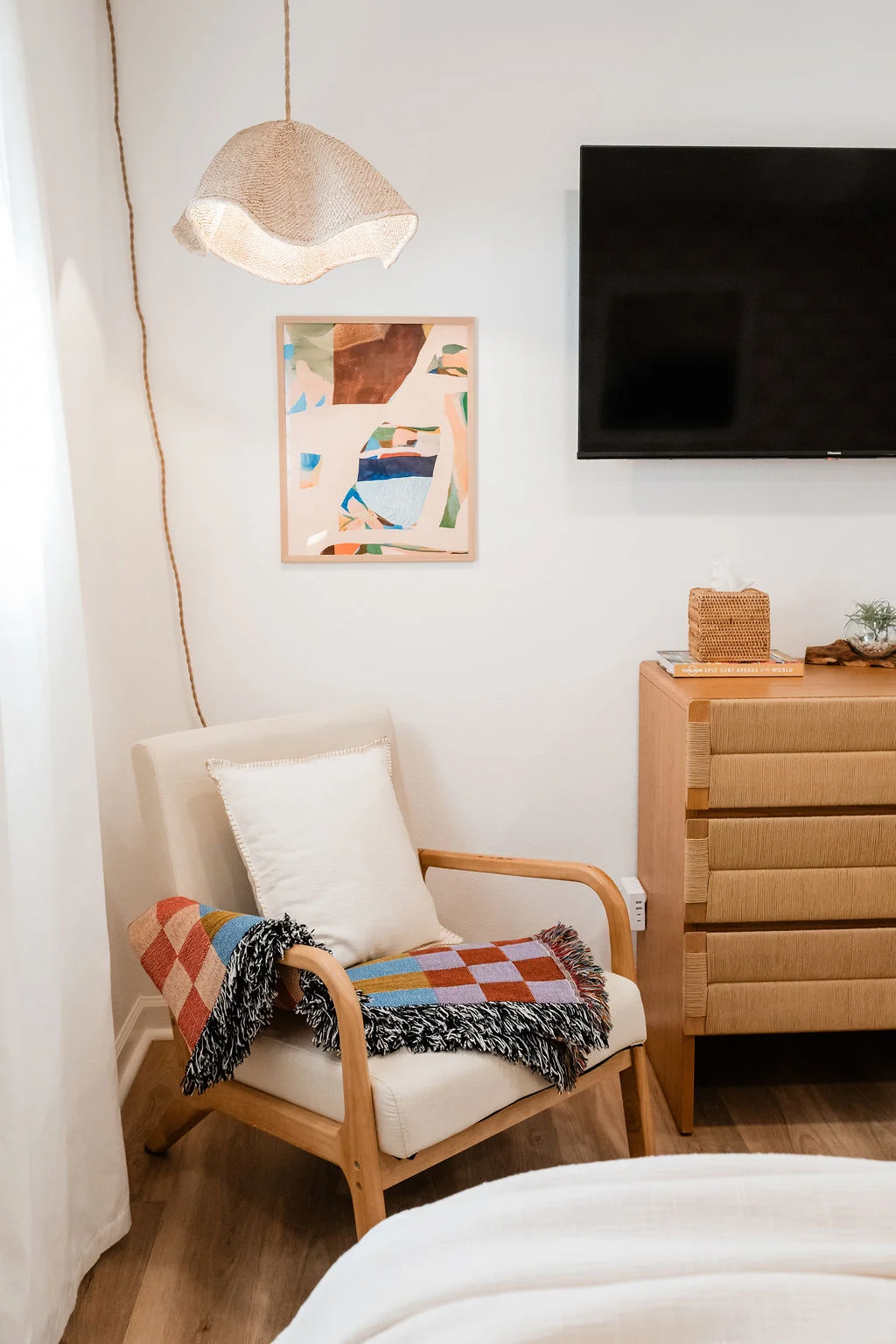 The Sundune Palm Springs primary bedroom lounge corner with wavy pendant lamp, rattan chair, and work station beyond