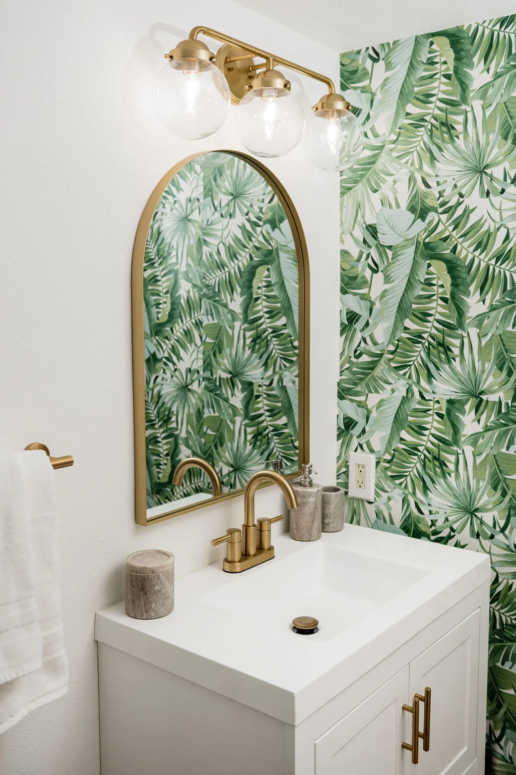The Sundune Palm Springs primary bathroom vanity detail with gold fixtures and palm wallpaper
