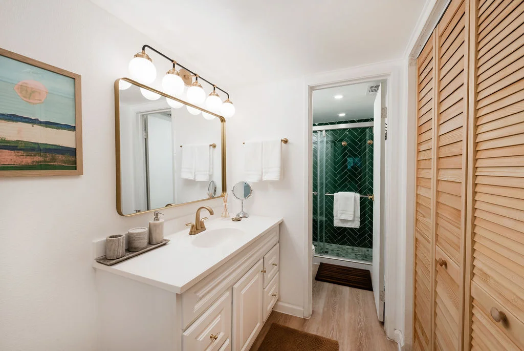 The Sundune Palm Springs second bathroom with gold vanity fixtures and emerald green herringbone tile