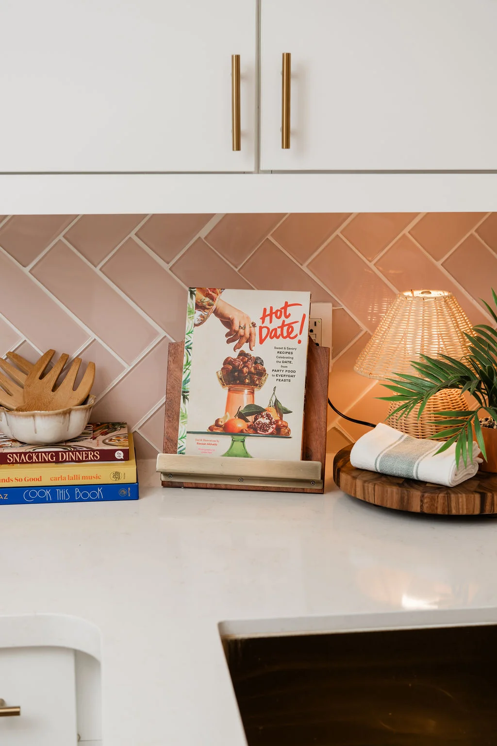 The Sundune Palm Springs kitchen counter with Hot Date cookbook, pink tile, and rattan pendant