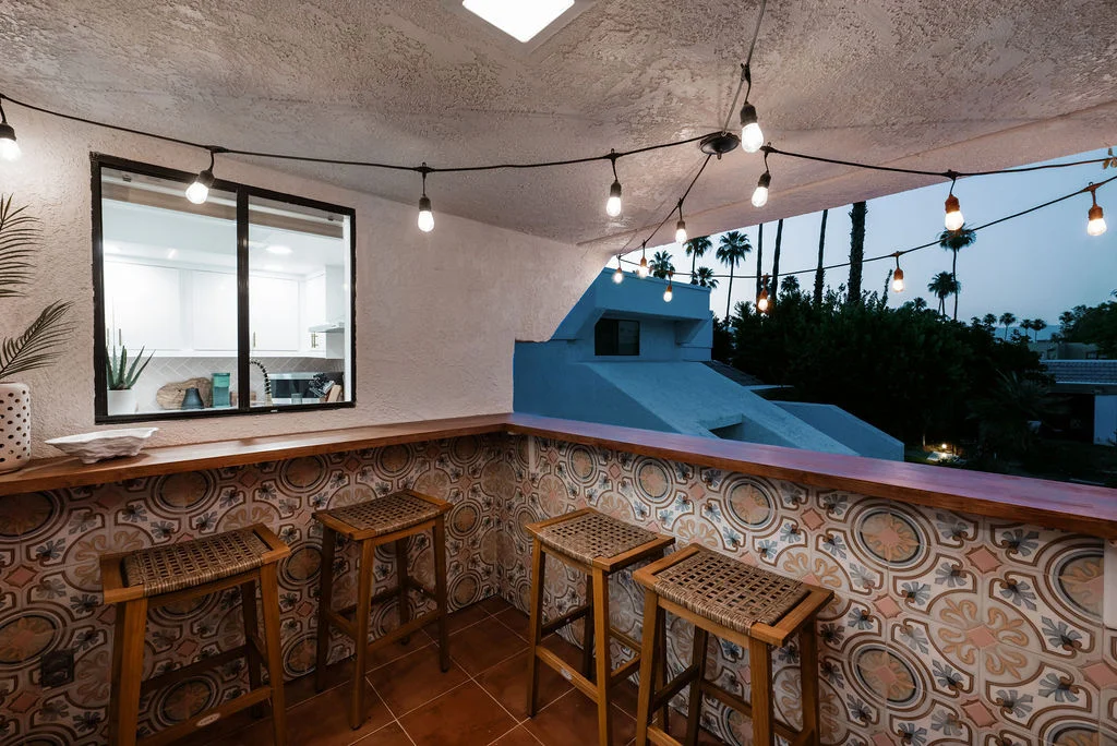 The Sundune Palm Springs terrace at dusk with string lights, bar stools, and desert sky